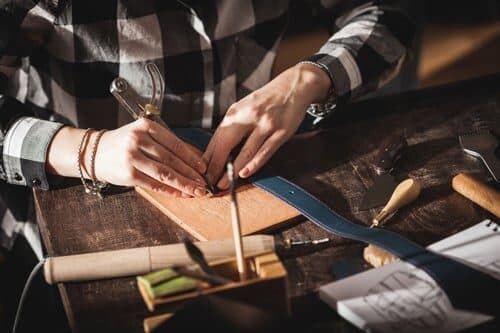 Artigiano al lavoro su una cintura in vera pelle nel laboratorio Emporium Italy
